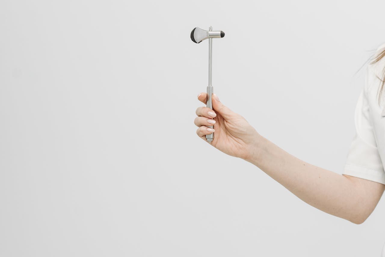 Detailed view of a reflex hammer held by a healthcare professional.